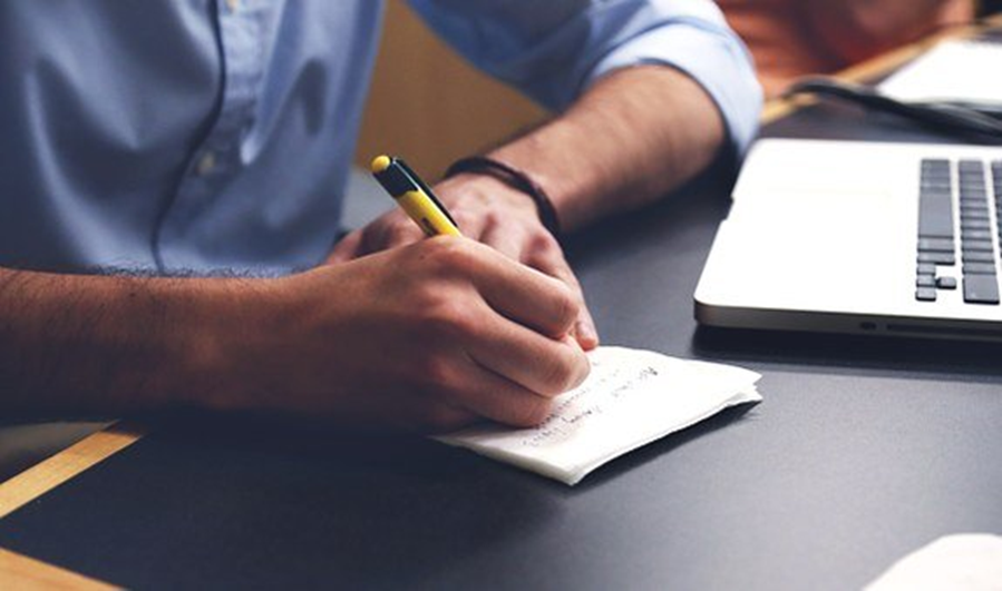 Un homme avec un stylo et du papier rédigeant un plan pour une entreprise d'escape room.