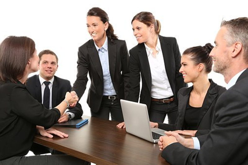 Hombres y mujeres trajeados discutiendo de negocios alrededor de una mesa.